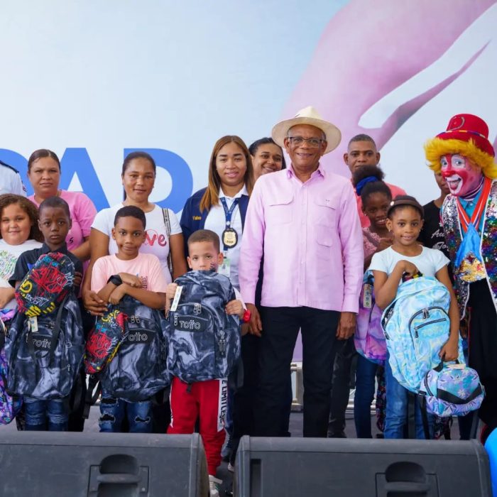 Director general posando con grupo de niños con mochilas escolares y sus padres empleados de la DGM, en conjunto con payaso en actividad de integración familiar.