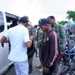 DGM officers checking foreigner in operation in front of white minibus and motorcycle stop.