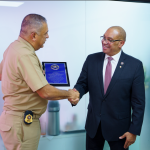 Director of Immigration shaking hands with the director of the United States Marshals Service (USMS) and receiving recognition for his collaboration.