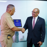 Director de Migración saludando con un estrecho de mano al director del Servicio de Marshals de Estados Unidos (USMS) y recibiendo un reconocimiento por su colaboración.