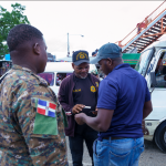 Agente migratorio deteniendo un extranjero e la calle para y esta verificando sus documentos con un militar al lado