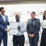 Ministro del MAP en entrega de reconocimiento a colaborador, en presencia de la directora de RRHH de la DGM en tarima.