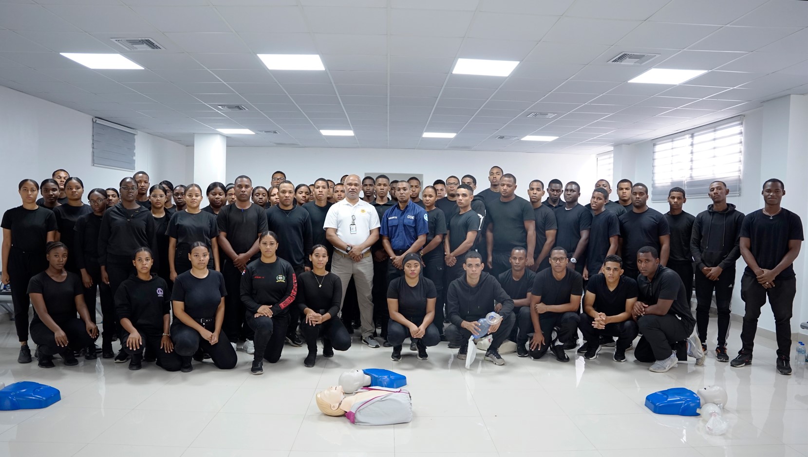 Group photo of agents in training in the multipurpose room for first aid agents.