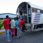 Irregular foreigners boarding a immigration control truck in rows at the Haina interdiction center.