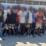 Extranjeros indocumentados frente a camión de control migratorio todos parados.