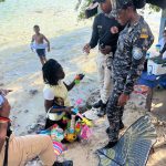 Immigration agent standing on the beach checking the document of a detained foreigner.