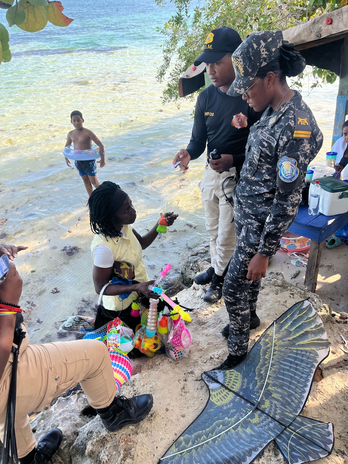 Immigration agent standing on the beach checking the document of a detained foreigner.