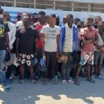 Extranjeros irregulares detenidos, todos parados frente a camión control migratorio.