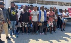 Extranjeros irregulares detenidos, todos parados frente a camión control migratorio.