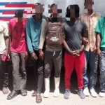Extranjeros indocumentados detenidos frente a camión de control migratorio