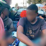 extranjeros ilegales detenidos montados en camioneta sentados.