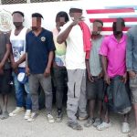 Illegal foreigners detained, all standing in front of an immigration control truck.