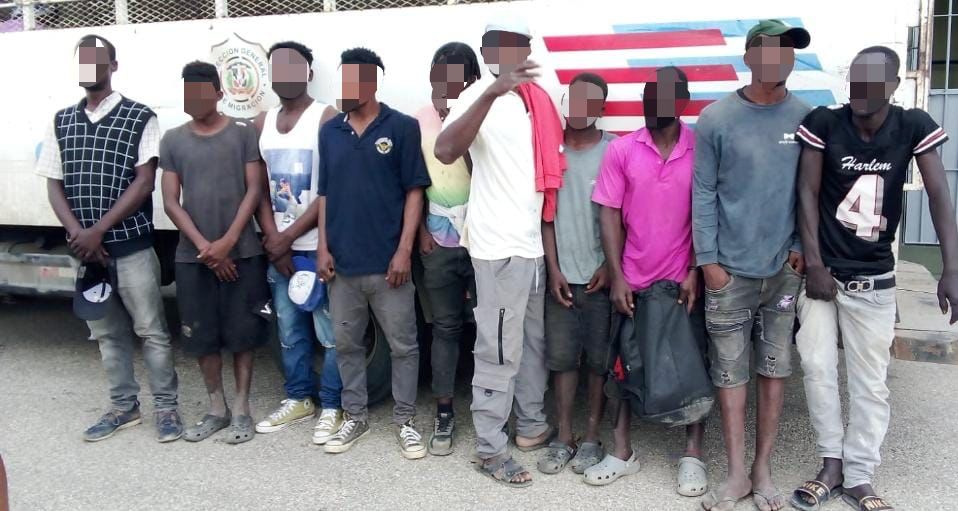 Illegal foreigners detained, all standing in front of an immigration control truck.