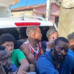 Extranjeros irregulares detenidos, todos sentados frente a camión control migratorio.