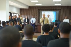 DGM Director welcoming the new rapid reaction unit in the UNICARIBE hall, the unit seated and DGM authorities standing.