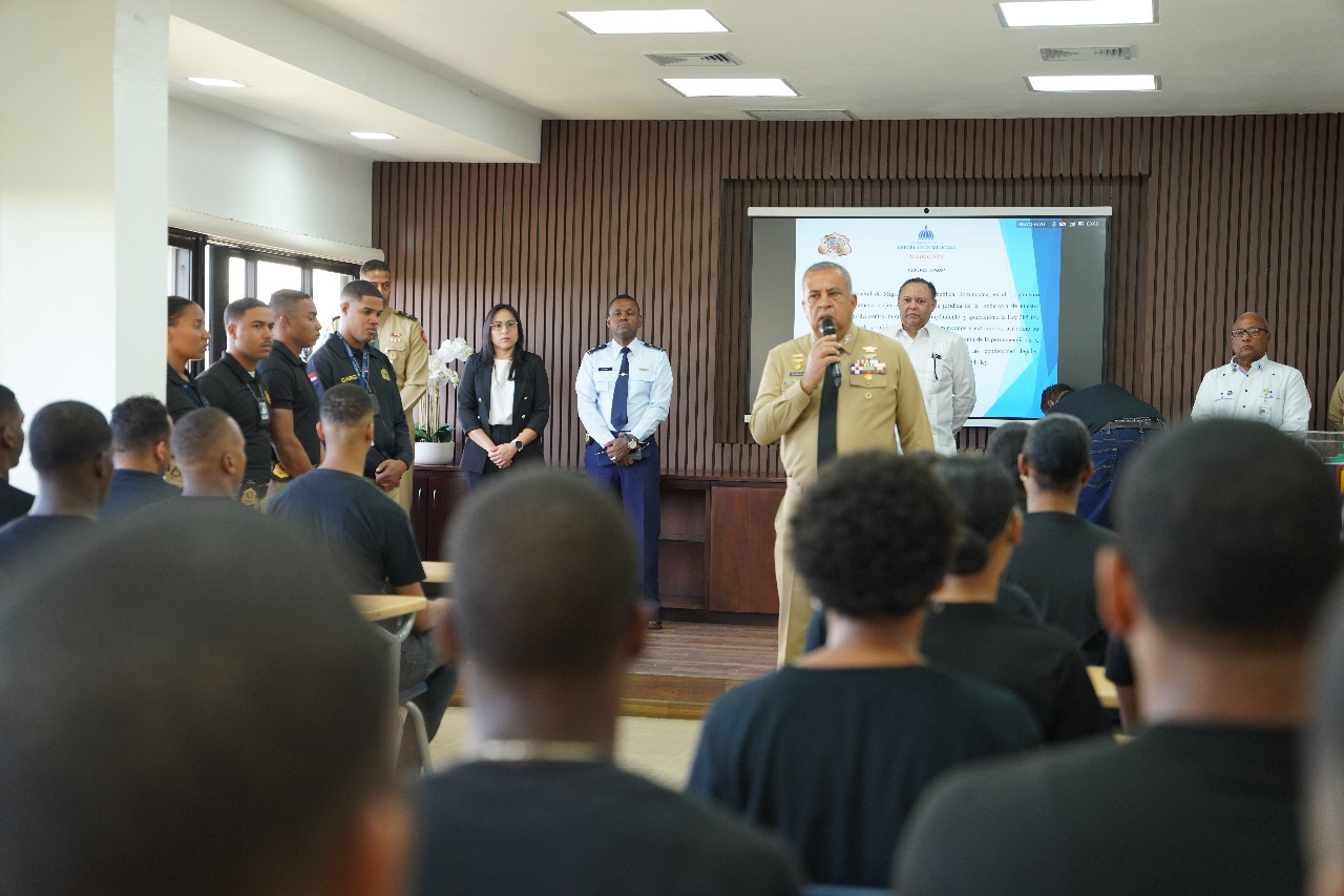 Director DGM dando bienvenida a nueva unidad de reacción rápida en salón de UNICARIBE, unidad sentada y autoridades DGM parados.