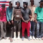 Extranjeros irregulares detenidos, todos parados frente a camión control migratorio.