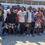 Extranjeros irregulares detenidos, todos parados frente a camión control migratorio.