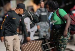 Immigration agent helping an undocumented foreigner carrying a suitcase.