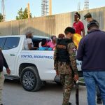 Immigration interdiction agents standing on the street, illegally loading foreigners into a van