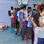 Extranjeros indocumentados, siendo ingresados a centro de detención y revisados por agentes migratorios
