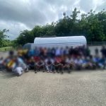 Illegal foreigners detained, all standing in front of an immigration control truck.