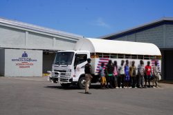 Immigration agent standing in front of a truck with undocumented foreigners at the Haina interdiction center.