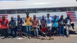 Extranjeros irregulares detenidos, todos parados frente a camión control migratorio.