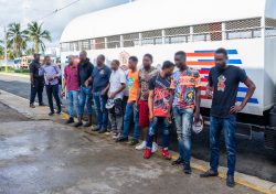 Extranjeros irregulares detenidos, todos parados frente a camión control migratorio.