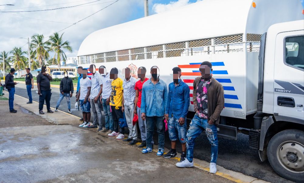 Illegal foreigners detained, all standing in front of an immigration control truck.